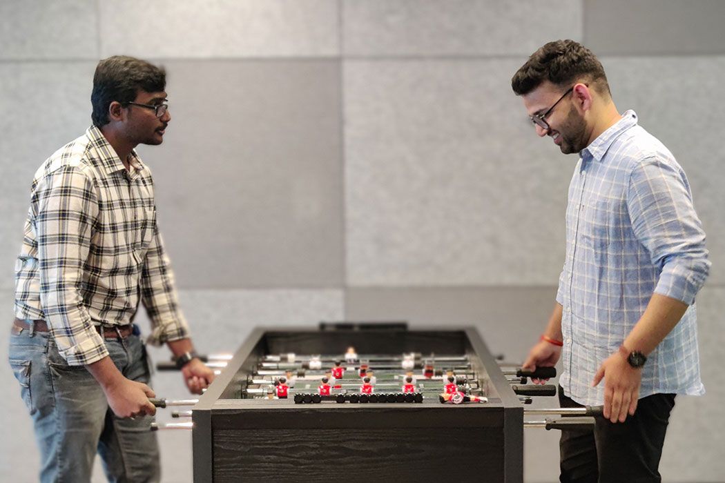 Two staff members playing foosball.