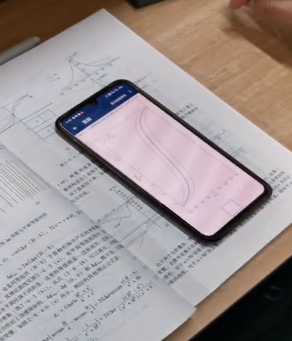 Libro de texto y teléfono móvil que muestran el procesamiento de datos geofísicos utilizando MATLAB Mobile.