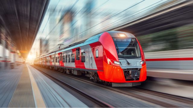 Tren eléctrico de pasajeros que circula a alta velocidad en un paisaje urbano