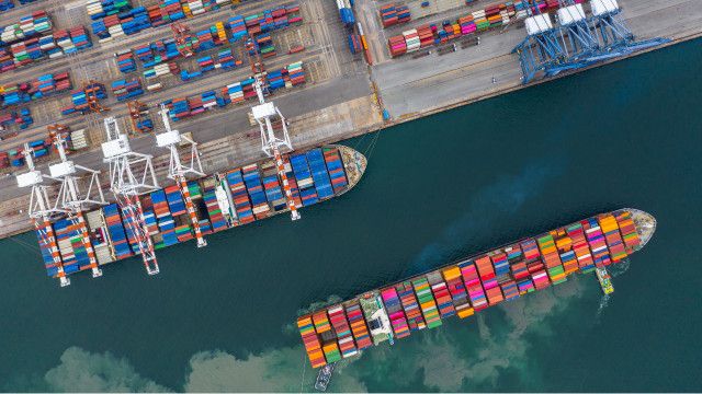 Vista aérea de una terminal de buques de carga con grúas de descarga, contenedores y buques portacontenedores